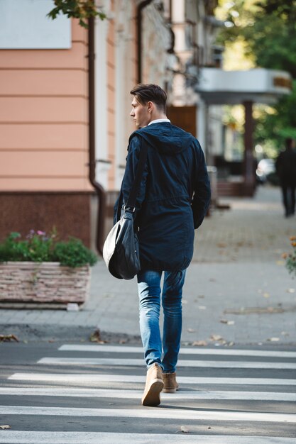 Junger Mann die Straße überqueren