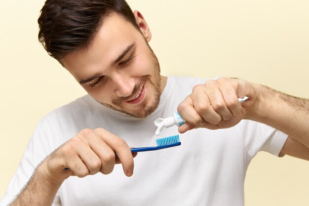 Junger Mann drückt Zahnpasta auf die Bürste