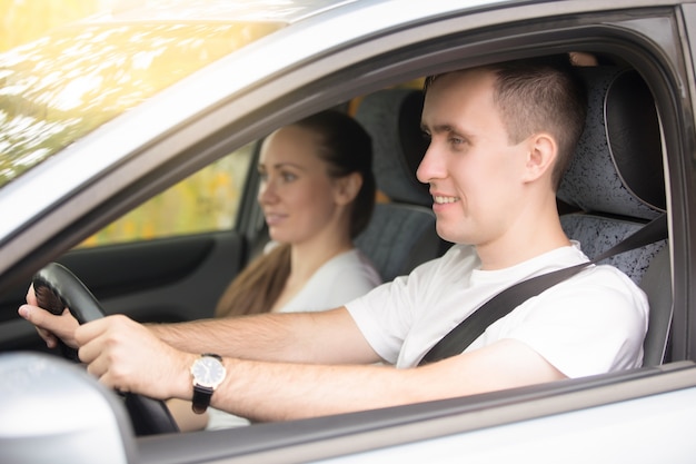 Junger Mann fährt und Frau sitzt in der Nähe des Autos