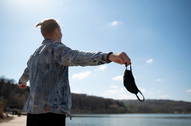 Kostenloses Foto junger mann feiert die aufhebung der gesichtsmaskenbeschränkungen im freien