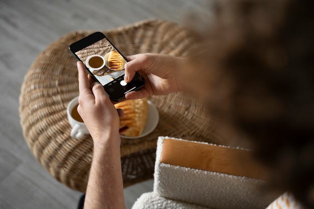 Junger Mann fotografiert sein Frühstück mit seinem Smartphone