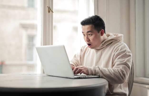 Junger Mann freut sich glücklich vor einem Computer