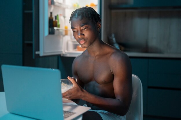 Kostenloses Foto junger mann genießt zu hause mitten in der nacht einen snack