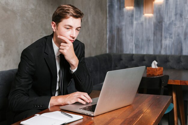 Junger Mann im Büro, das an dem Laptop arbeitet