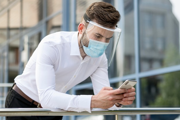 Kostenloses Foto junger mann im freien mit maskenprüfmobil