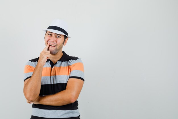 Junger Mann im gestreiften T-Shirt, Hut, der unter Zahnschmerzen leidet und schmerzhaften Raum für Text sucht