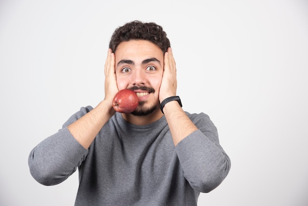 Junger Mann im grauen Sweatshirt, der Apfel in seinem Mund hält.