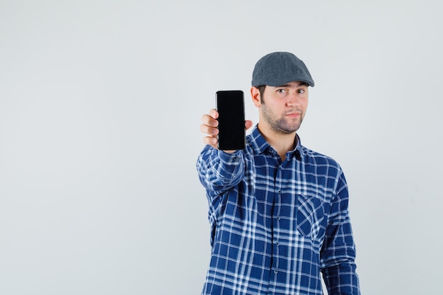 Junger Mann im Hemd, Kappe, die Handy zeigt und selbstbewusst, Vorderansicht schaut.