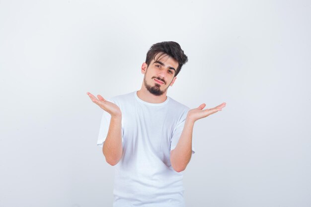 Junger Mann im weißen T-Shirt zeigt hilflose Geste und sieht verwirrt aus