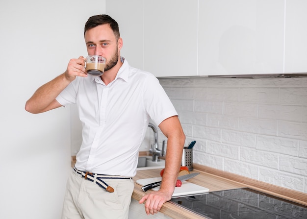 Kostenloses Foto junger mann in der küche einen kaffee genießend