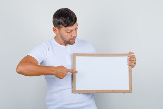 Junger Mann in der weißen Uniform, die etwas an Bord zeigt, Vorderansicht.