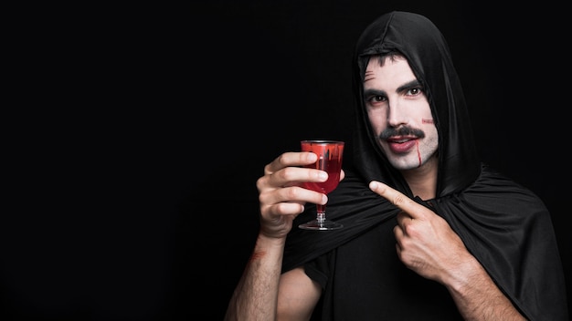 Junger Mann in Halloween-Kostüm, das Weinglas hält