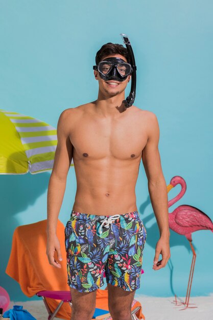 Junger Mann in tragender Schwimmenmaske und -c $ lächeln der Badebekleidung