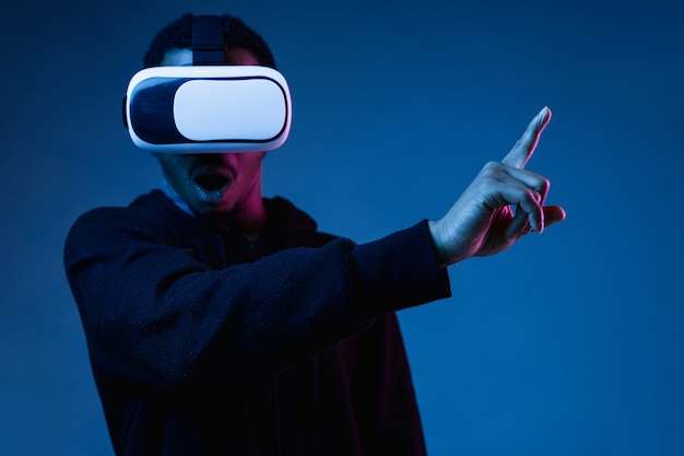 Junger Mann in VR-Brille im Neonlicht auf Blau