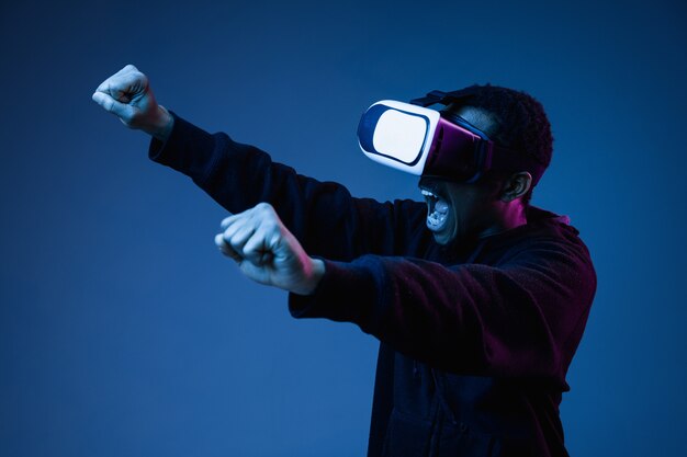 Junger Mann in VR-Brille in Neon auf Blau