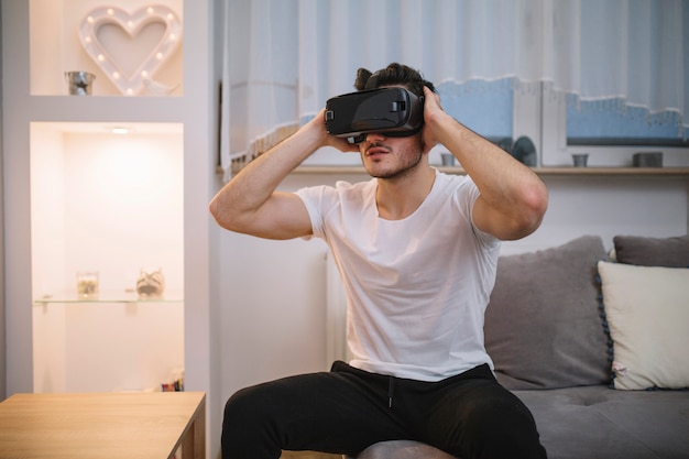 Junger Mann in VR-Gläsern auf Sofa