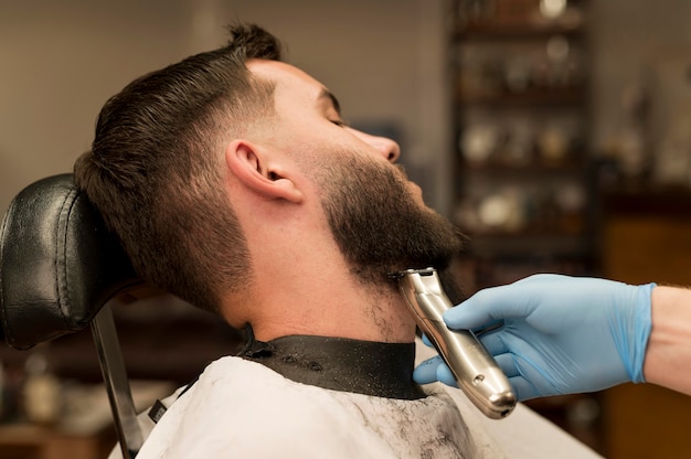 Junger Mann lässt sich beim Friseur seinen Bart stylen