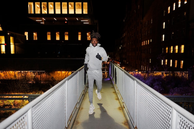 Junger Mann läuft nachts auf einer Brücke in der Stadt