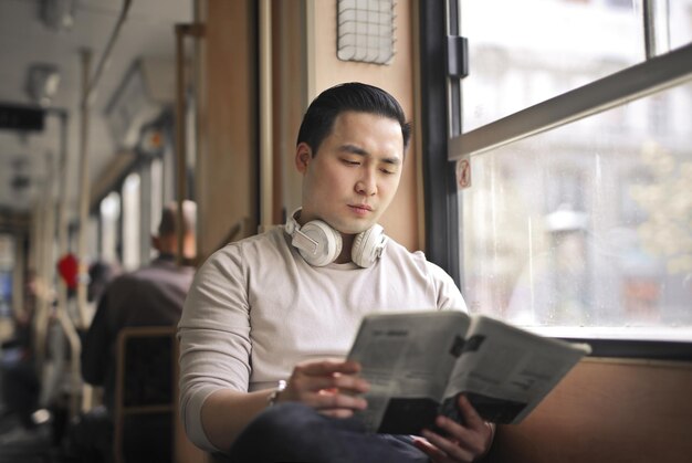 junger mann liest eine zeitung in einer straßenbahn