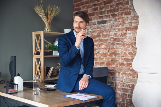 Junger Mann, Manager, Team führte nach der Quarantäne die Rückkehr zur Arbeit in sein Büro, fühlt sich glücklich und inspiriert