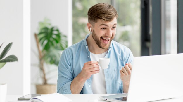 Junger Mann mit Airpods, die am Laptop arbeiten