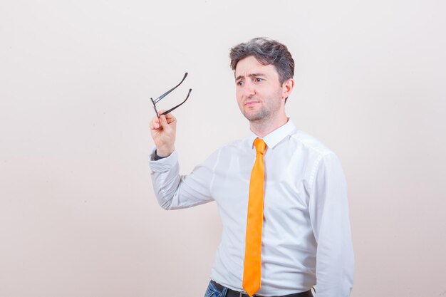 Junger Mann mit Brille in Hemd, Jeans und unzufriedenem Blick