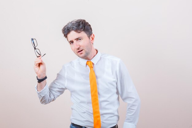 Junger Mann mit Brille in Hemd, Jeans und verwirrtem Blick