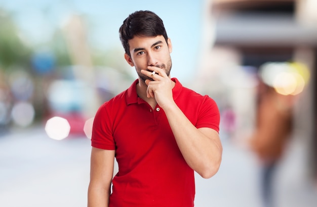 Junger Mann mit dem roten T-Shirt, das eine Zigarette