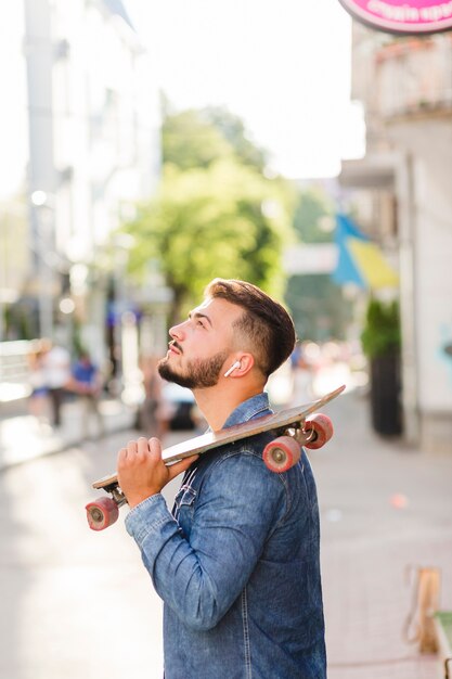 Junger Mann mit dem Skateboard, das oben schaut