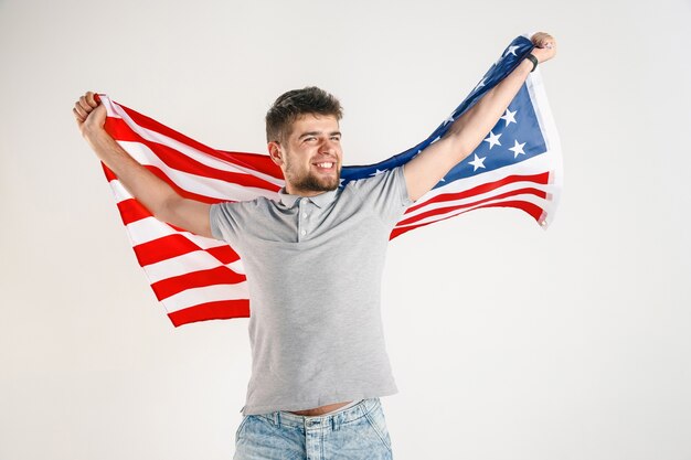 Junger Mann mit der Flagge der Vereinigten Staaten von Amerika lokalisiert auf weißem Studio.