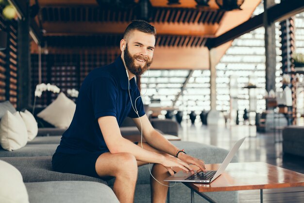 junger Mann mit einem Bart arbeitet in einem Café, Freelancer nutzt einen Laptop, macht ein Projekt