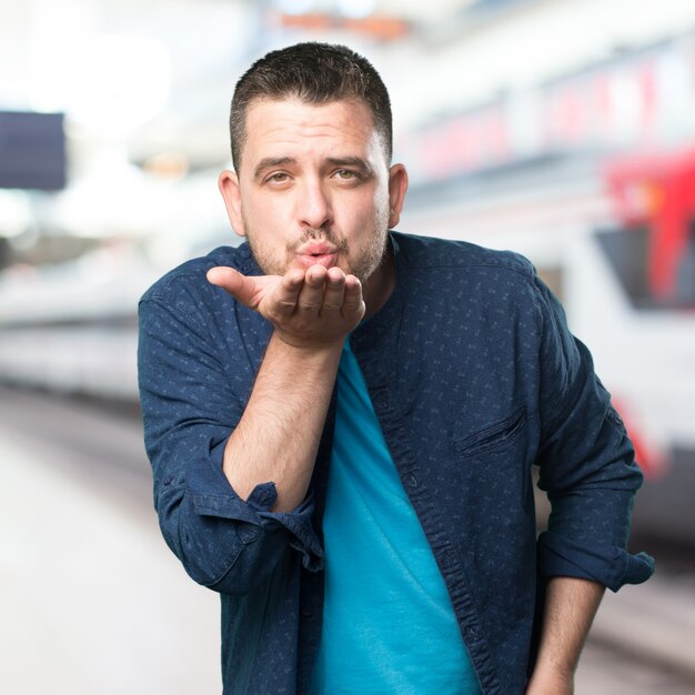 Junger Mann mit einem blauen Outfit tragen. Blasen einen Kuss.