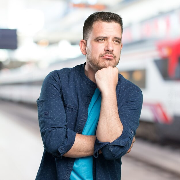 Junger Mann mit einem blauen Outfit tragen. Blick nachdenklich.