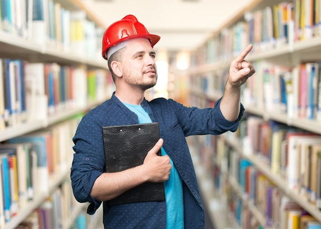 Kostenloses Foto junger mann mit einem blauen outfit tragen. das tragen von roten helm. zeigt auf