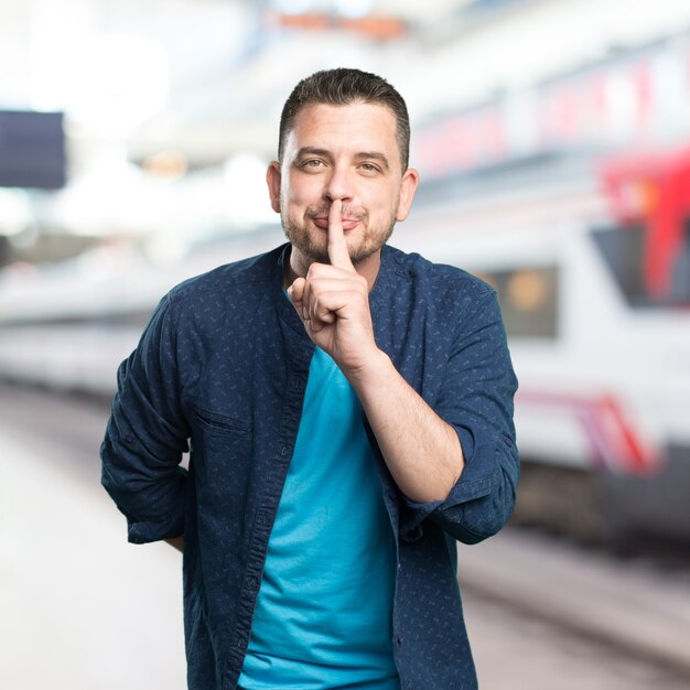 Junger Mann mit einem blauen Outfit tragen. Doing Stille Geste.