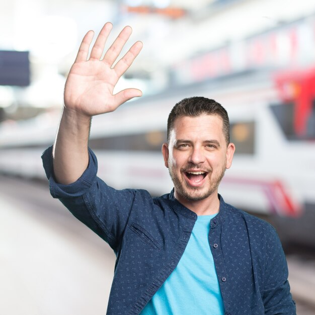 Junger Mann mit einem blauen Outfit tragen. Greting Geste.