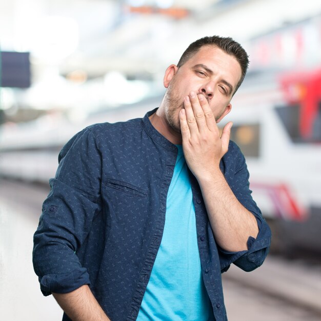 Junger Mann mit einem blauen Outfit tragen. Suchen Sie schläfrig.