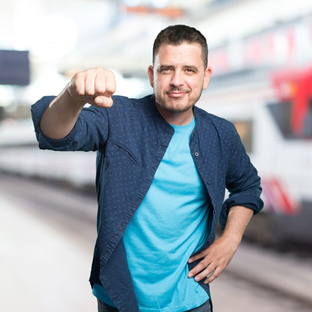 Junger Mann mit einem blauen Outfit tragen. Zeigt seine Faust zuversichtlich.