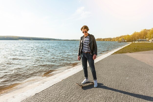 Junger Mann mit einem Skateboard nahe dem Meer