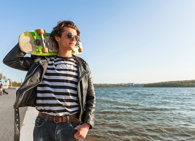 Kostenloses Foto junger mann mit einem skateboard nahe dem meer