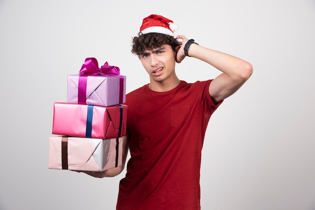 Kostenloses Foto junger mann mit geschenkboxen, die kopfschmerzen haben.