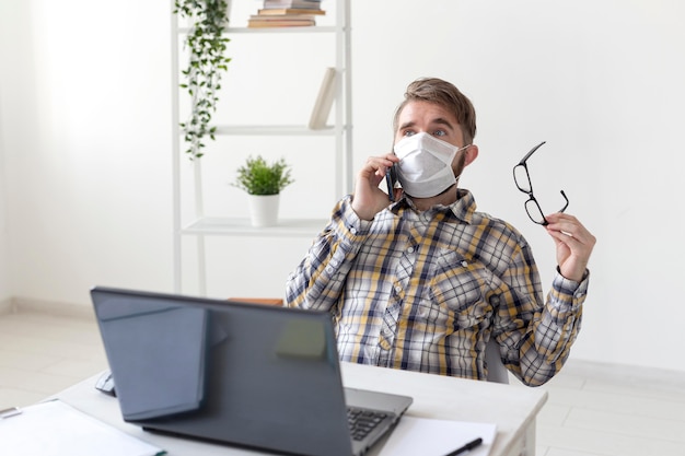 Kostenloses Foto junger mann mit gesichtsmaske, die am telefon spricht