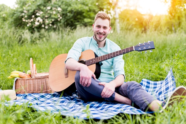 Junger Mann mit Gitarre auf Picknick