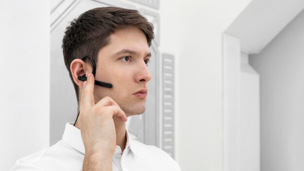 Junger Mann mit Handprototyp, der Bluetooth-Kopfhörer aktiviert