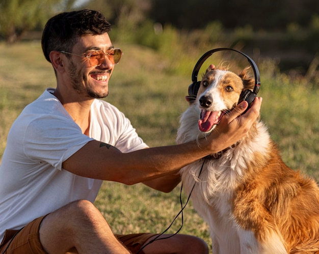 Junger Mann mit Hund am Meer mit Kopfhörern