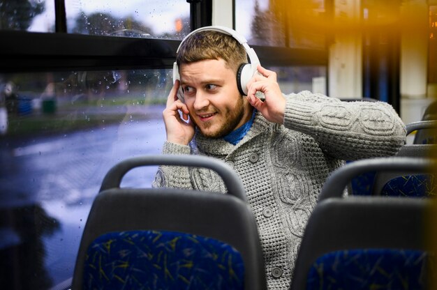 Junger Mann mit Kopfhörern auf dem Sitz des Busses