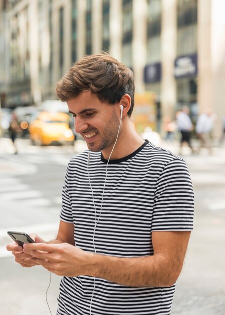 Junger Mann mit Kopfhörern schreibend an einem Telefon