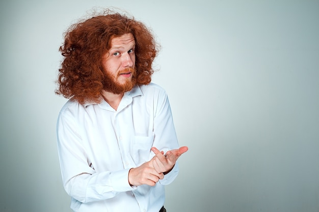 junger Mann mit langen roten Haaren, die Kamera betrachten, die auf Fingern zählt