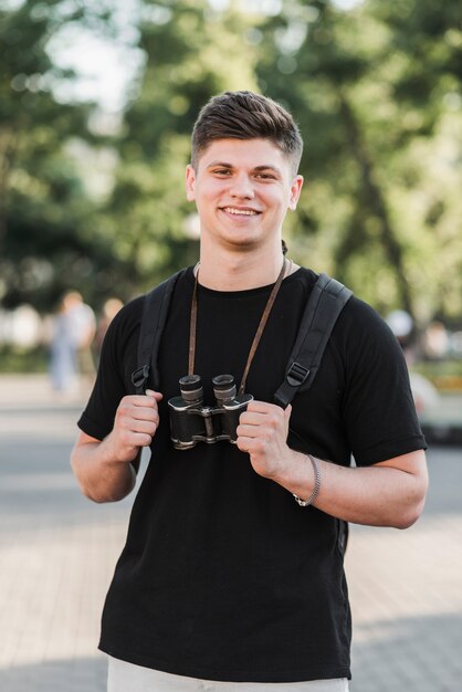 Junger Mann mit Rucksack und Ferngläsern