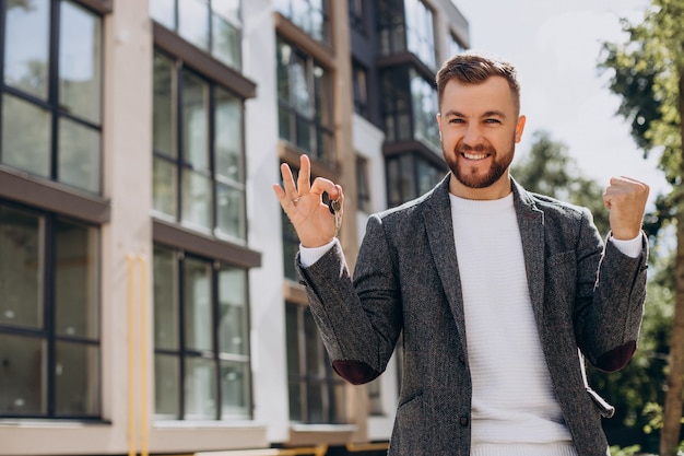 Junger Mann mit Schlüssel hat gerade eine neue Wohnung gekauft